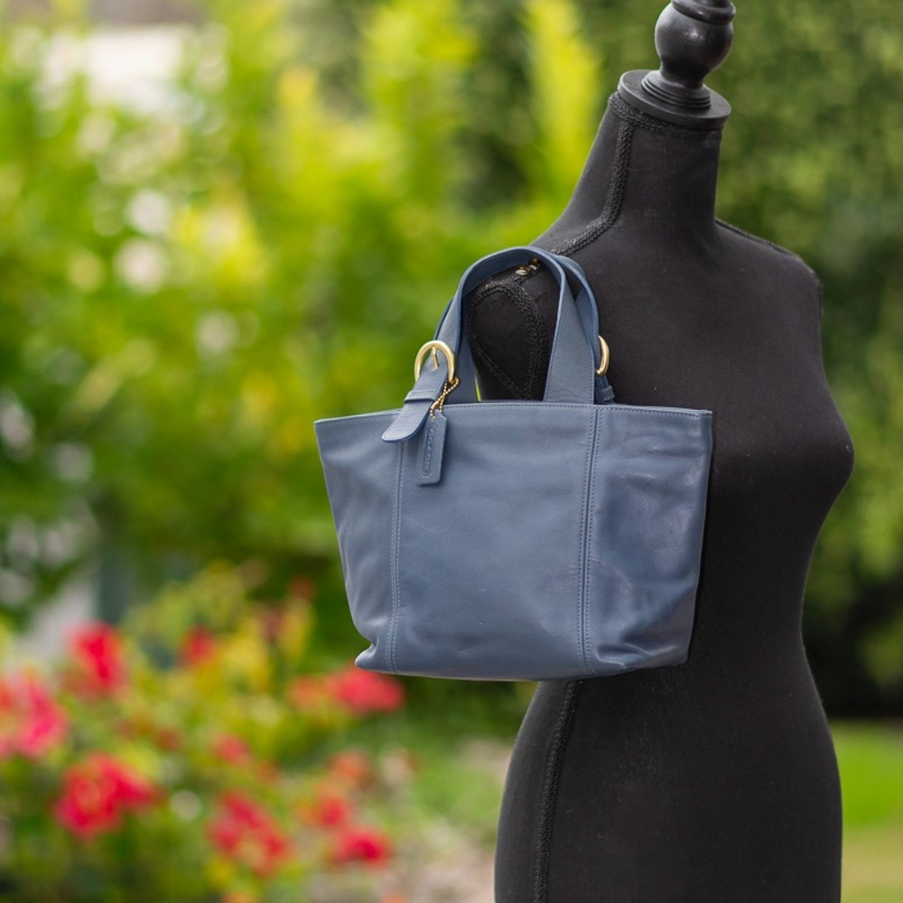 Coach blue leather handbag with gold accent hardware.